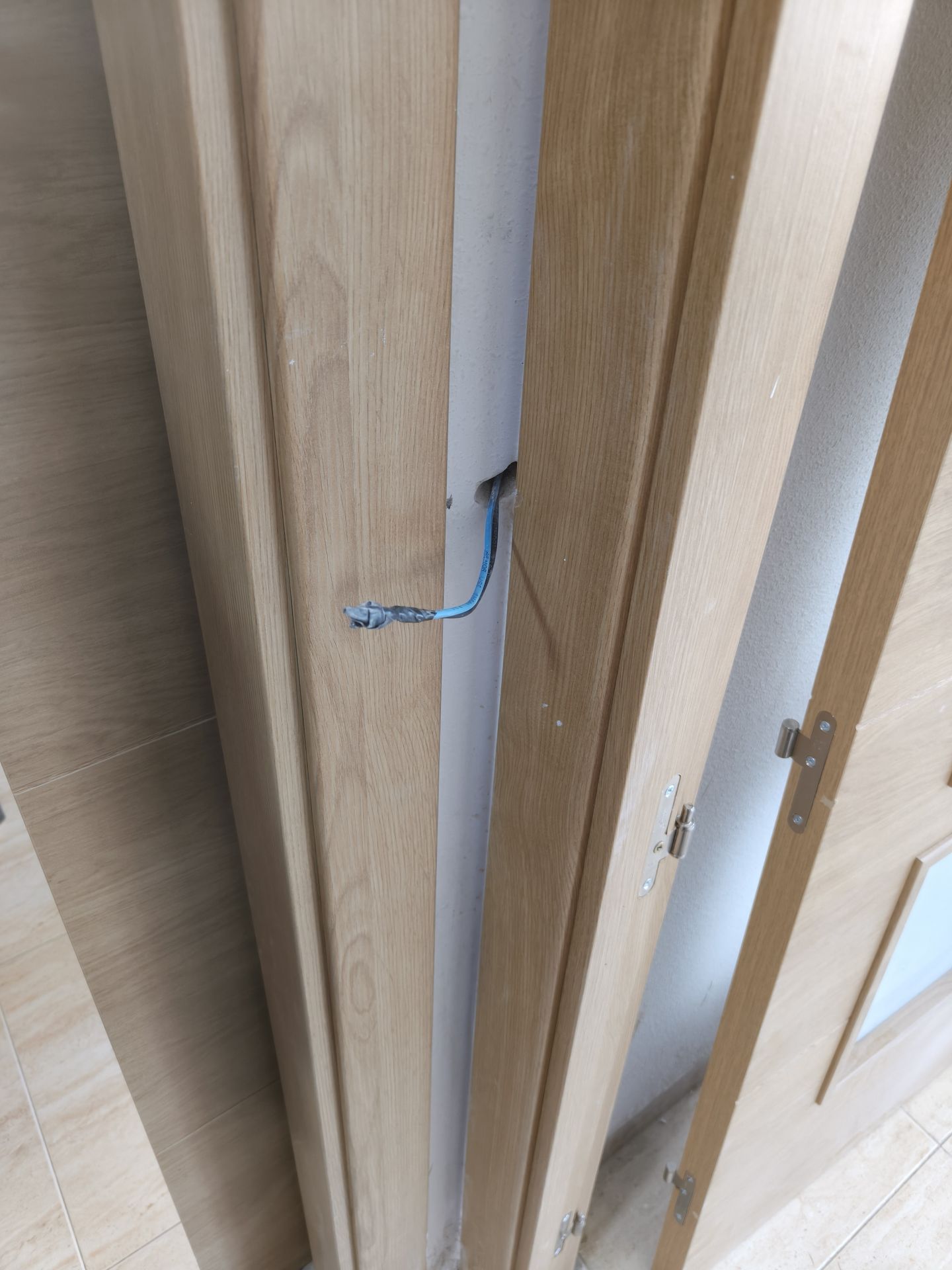 Cable eléctrico sobresaliendo del marco de una puerta en una obra revisada en Amposta, ejemplo de instalación incorrecta y poco profesional.
